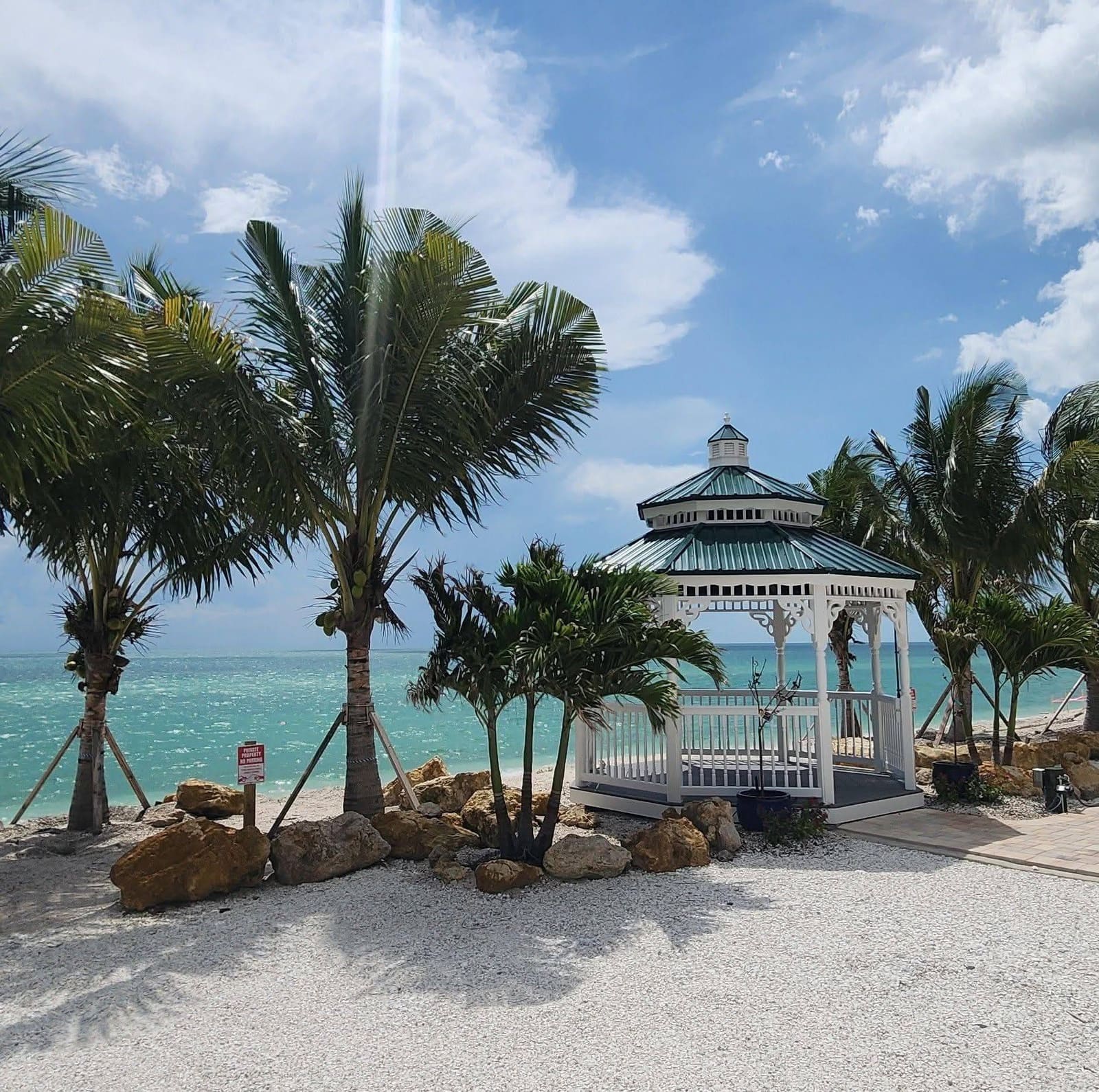 Coconut palms and rock landscaping around a waterfront gazebo in Southwest Florida