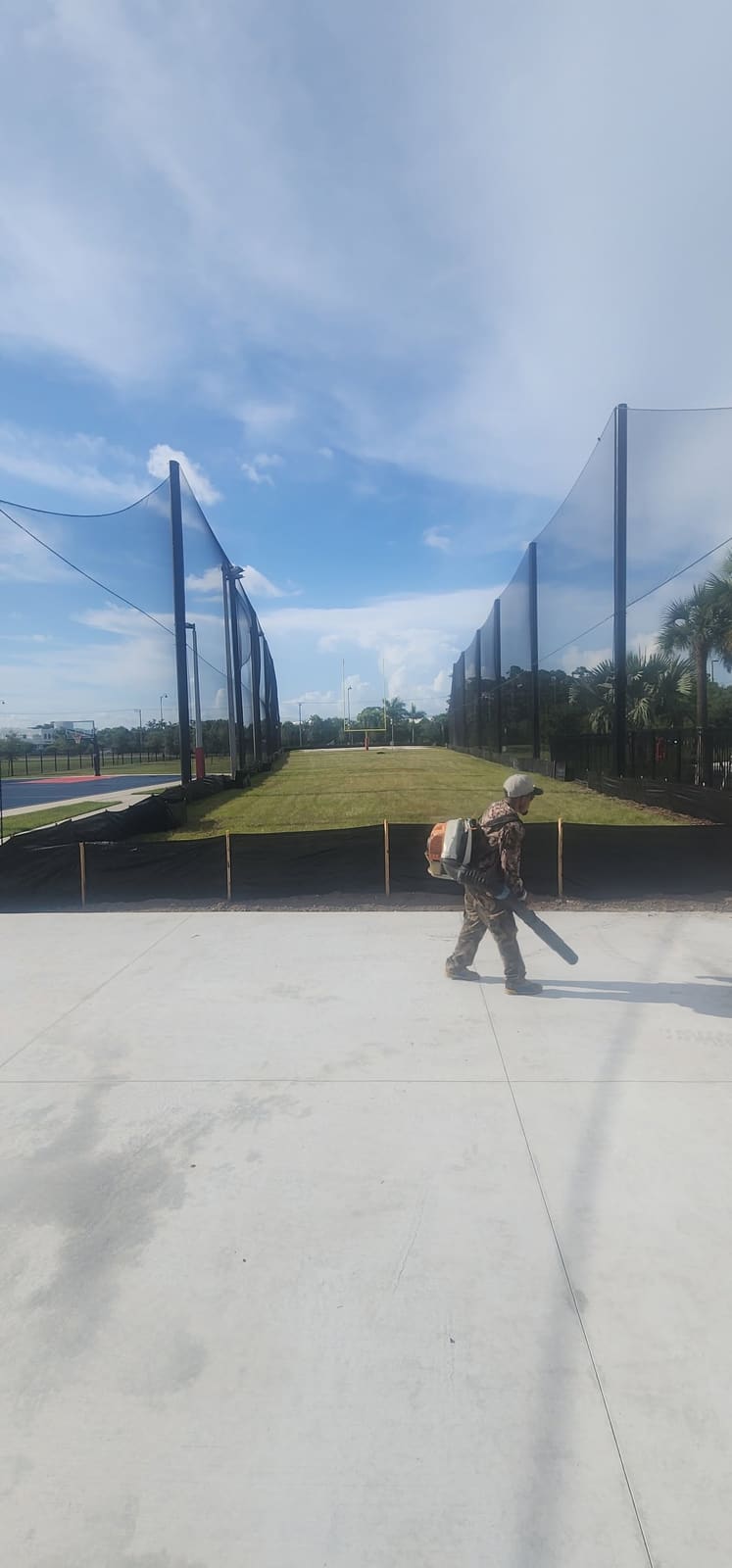 Crew member clearing a sports court with a backpack blower